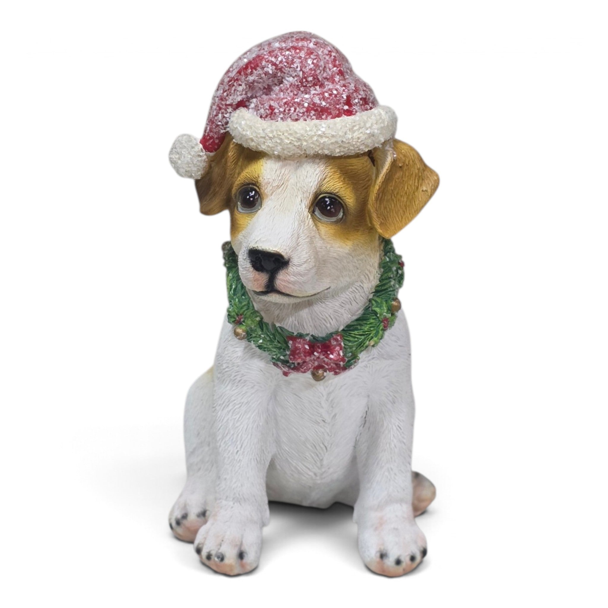 A small sitting dog figurine with white and tan fur, wearing a red glittery Santa hat with white trim and a green garland with a pink bow, photographed on a plain white background.