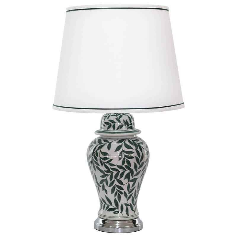 Decorative lamp with a white shade and leaf-patterned base on a white background