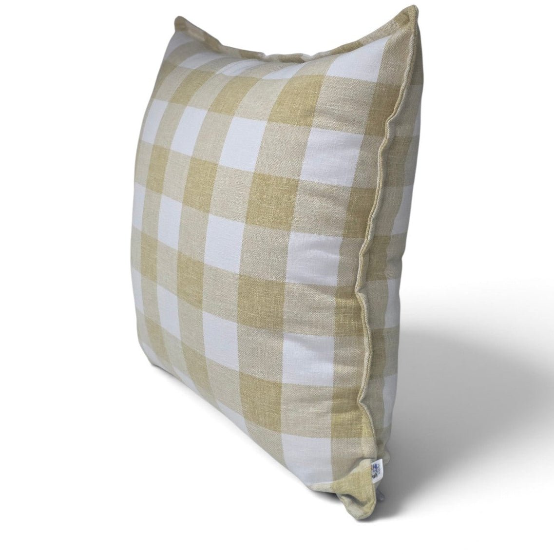 A square throw pillow featuring a classic gingham check pattern in beige and white, shown at a three-quarter angle on a white background with a soft shadow.