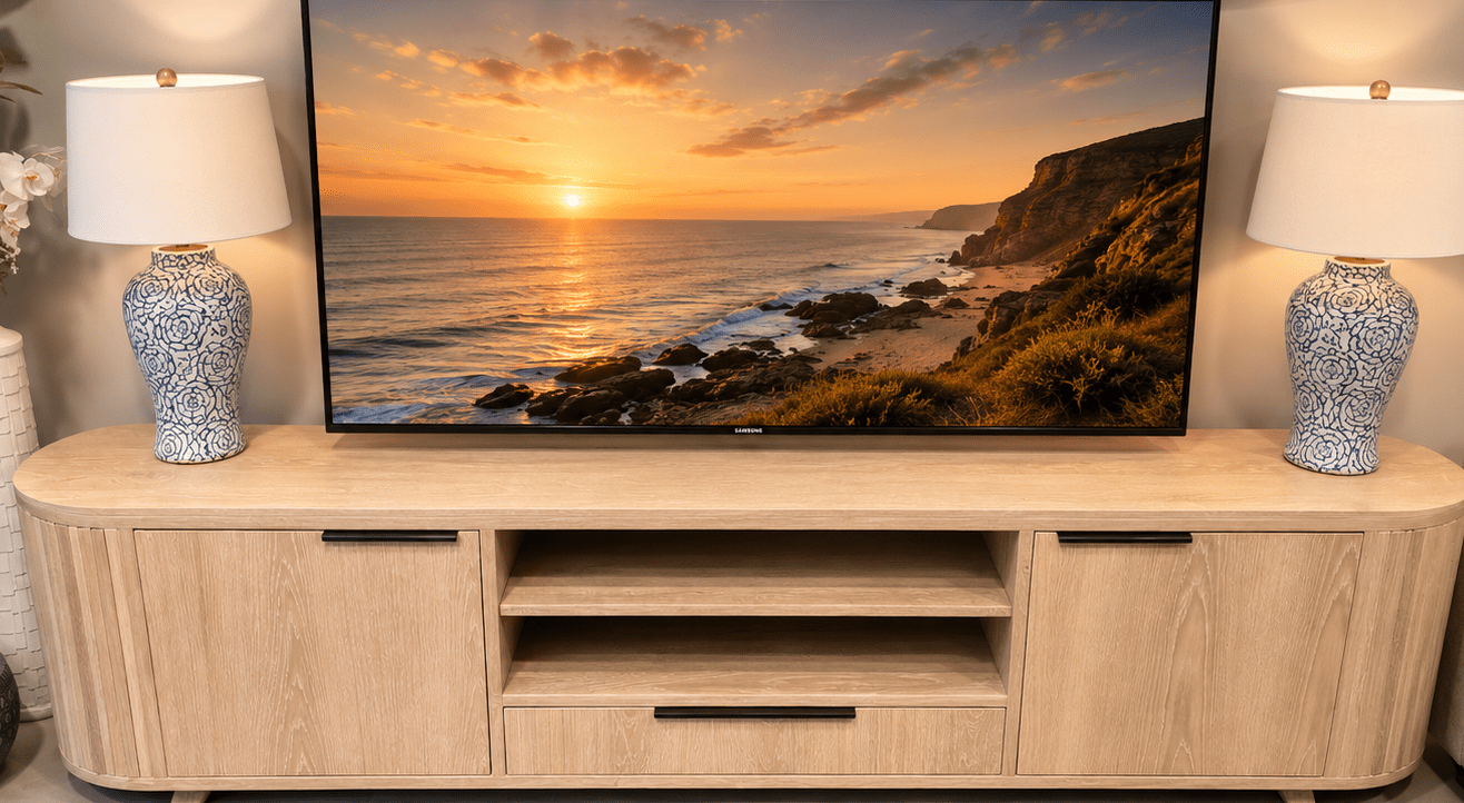TV on a wooden stand with sunset over ocean scene, flanked by two lamps in a living room.