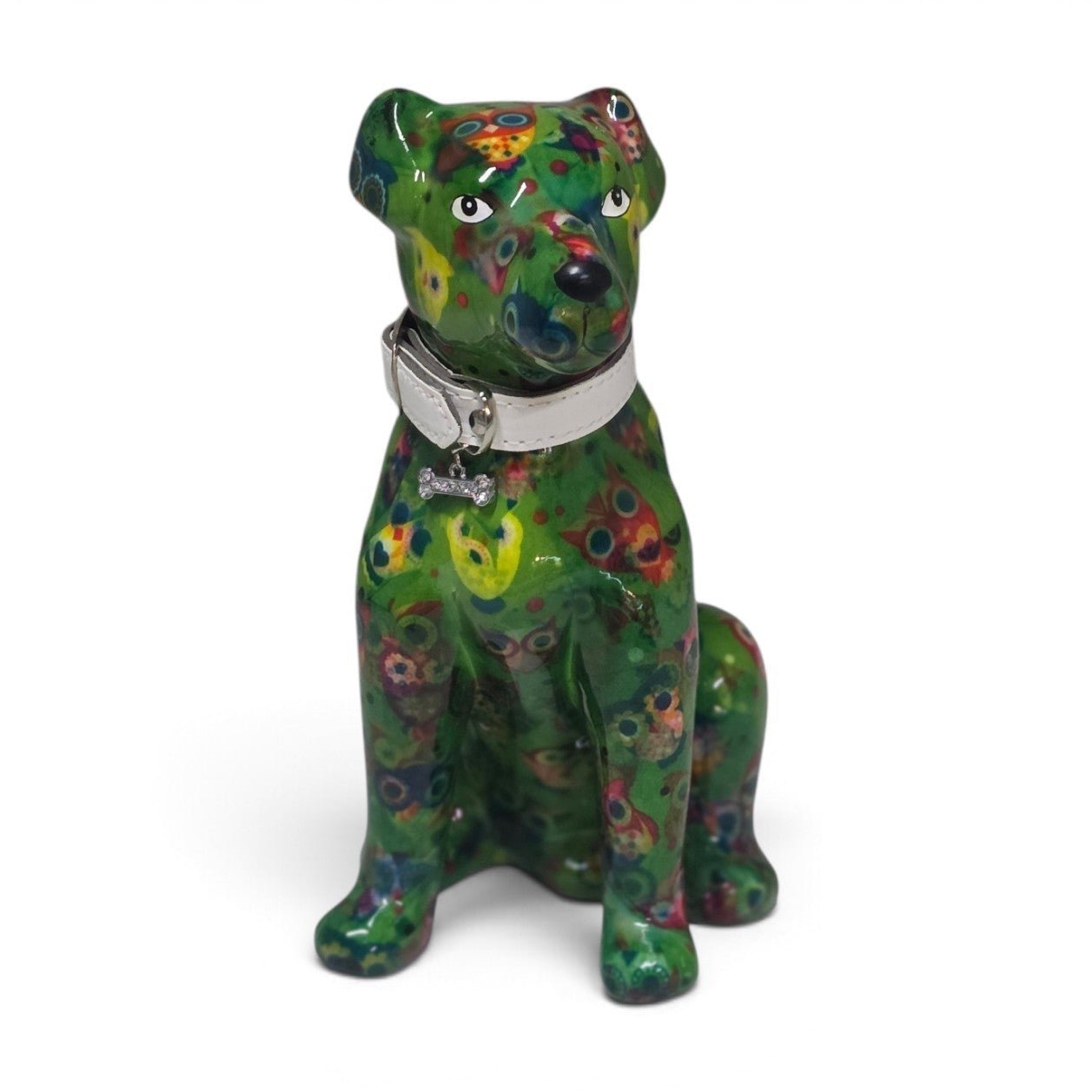 A glossy ceramic dog figurine in a sitting position, decorated with a vibrant green base and multicolored floral patterns, wearing a silver collar with a small crown tag.